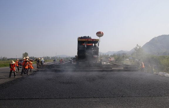 2019年8月，宜春經(jīng)開區(qū)S311路面攤鋪現(xiàn)場，工友們輔助路面兩側(cè)的分料、補窩等作業(yè)